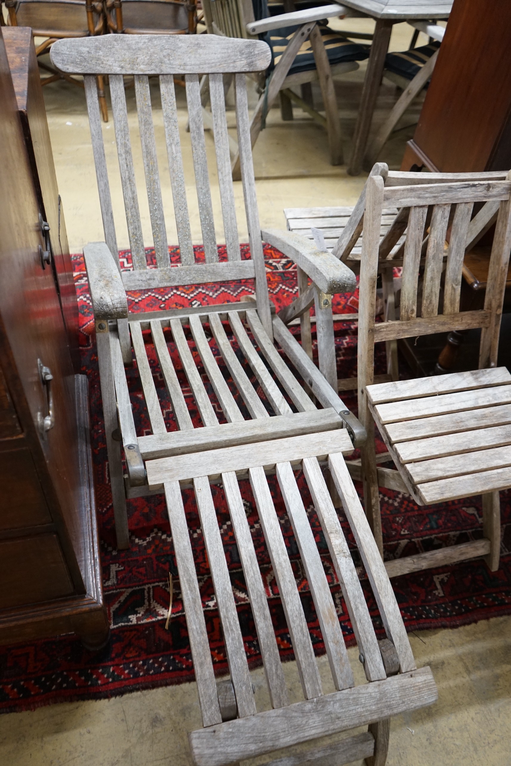 A weathered teak garden steamer chair and two folding garden chairs